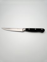 שולחן אוכל ערוך עם סט סכיני סטייק משוננות של ASF ליד כל צלחת.