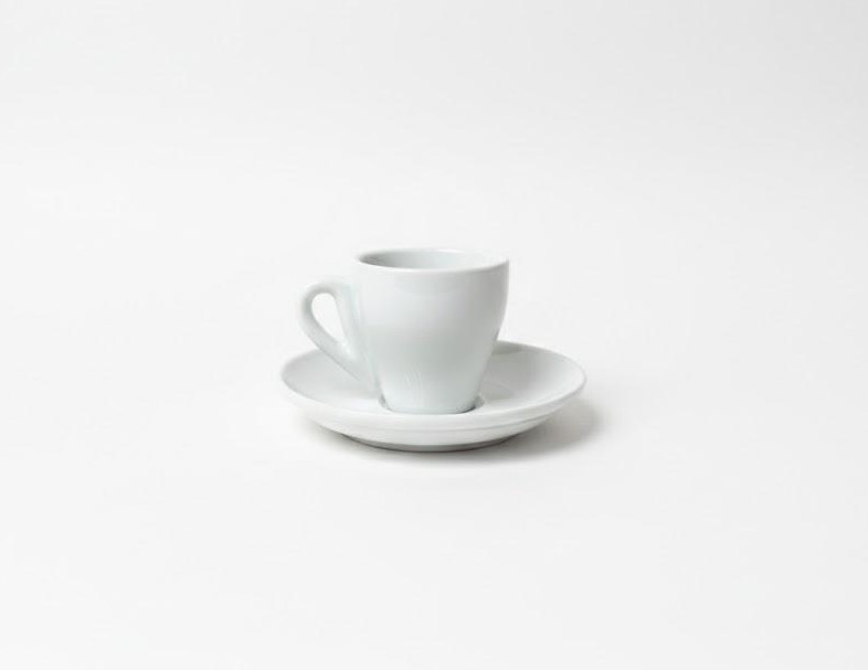 צילום מוצר נקי של ספל אספרסו פורצלן איכותי עם ידית ארגונומית. זוג ספלי אספרסו ותחתיות תואמות מפורצלן לבן על רקע נקי. מבט מהצד על סט ספל ותחתית לאספרסו בעיצוב אירופאי קלאסי.