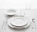 קלוז-אפ על מערכת כלי האוכל Bauscher Mozart, הכוללת צלחות עגולות וקערת מרק, מונחת על שולחן חג עם סכו"ם וקישוטים מודרניים.