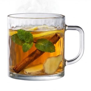 חליטת תה צמחים עשירה בכוס זכוכית עם פסים גליים, נענע ומקל קינמון.