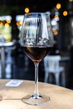 תמונה מקרוב של כוס יין Adora מלאה, המדגישה את צבע היין ואת הברק של הזכוכית.