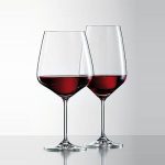 זוג כוסות יין קריסטל אלגנטיות, בעלות צורה קלאסית ורגל ארוכה. הכוסות מלאות ביין אדום עשיר, והברק הקריסטלי שלהן בולט על רקע לבן. מושלם לאירוח חברים או לערב רומנטי