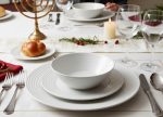 שולחן חג ערוך ואלגנטי עם סט צלחות Arcoroc פסים וכלי כסף.