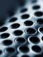 סכין שף Global G-78 עם חריצים, מונחת על קרש חיתוך לצד ירקות כמו בצל ותפוחי אדמה.