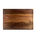 בוצ'ר מעץ שיטה עבה עם חריץ לניקוז נוזלים, מונח על משטח עבודה במטבח.