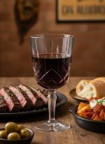 על שולחן ערוך בקפידה במסעדה, כוס Noblesse של Nachtmann עם יין אדום, המשדרת יוקרה ועידון, ומוסיפה נופך קלאסי לחוויית הסעודה.