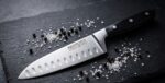 סכין Nirosta Trinity בשימוש שף מקצועי לחיתוך דק ומדויק של בצל וירקות שורש.