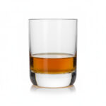 כוס וויסקי אנבי מעוצבת, מלאה במידה קטנה של וויסקי זהוב, מונחת על רקע סטודיו לבן ומדגישה את הצלילות והצורניות הייחודית של הכלי.