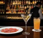 כוס מרטיני Royal Leerdam עם זית, מוגשת על דלפק בר יוקרתי לצד צלחת קרפצ'ו.