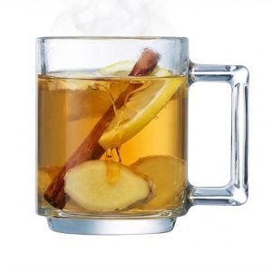 כוס תה חם עם לימון ונענע מוגשת לצד פרוסת עוגת גזר בסלון ביתי.