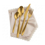 סט סכו"ם Salvinelli Fast Ice Gold מונח בתוך מפית בד בגוון שמנת-פנינה עם עיטורי תחרה עדינים.