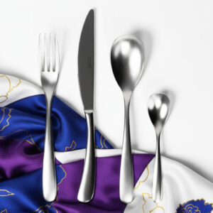 סט סכו"ם Salvinelli Forever מונח על מפית בד יוקרתית עם הדפס כחול וזהב על רקע לבן.