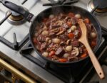 תבשיל בקר ברוטב עשיר מתבשל בתוך מחבת סוויס דיאמונד 24 ס"מ המונחת על כיריים יוקרתיות.