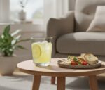 רגע של מנוחה עם משקה קר בכוס מעוצבת לצד עציץ ונוף ביתי נעים.