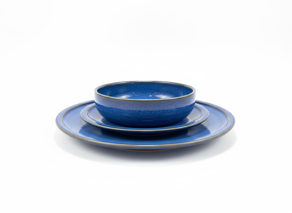 צילום מוצר מקצועי של כלי אוכל RAK כחולים ועמידים על רקע לבן בוהק. שלישיית צלחות בגדלים שונים מהסדרה הכחולה של RAK על רקע לבן קלאסי.