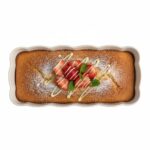 עוגת פירות מעוטרת בתוך תבנית Emile Henry על שולחן עץ בסגנון אירופאי.