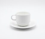 זוג ספלי קפוצ'ינו ותחתיות מפורצלן Bone China לבן של מותג העילית Arthur Krupp על רקע לבן.